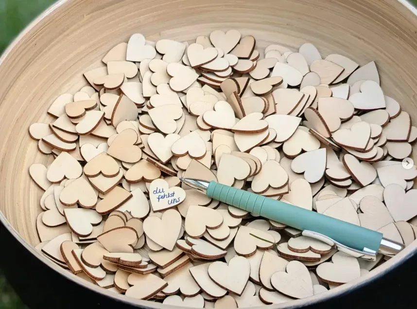 Eine Schale mit Holzherzen, auf eines ist „du fehlst uns“ geschrieben